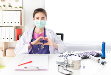 asian female doctor wear surgical mask and show heart sign with hand in hospital, she want to pollution protection and virus protection, healthcare and infection control, corona virus