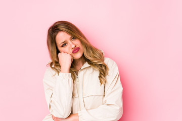 Young caucasian woman isolated on pink background who feels sad and pensive, looking at copy space.