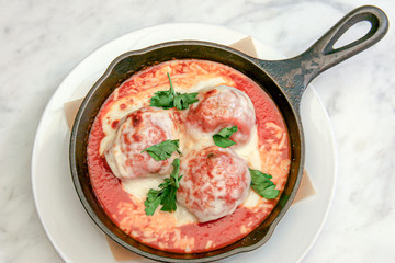 Exquisite Meatballs With Melted Cheese Presented Artistically in a hot Iron Skillet