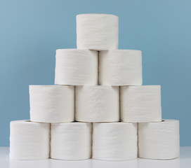 Rolls of toilet paper stacked on table against blue background