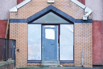 Derelict closed housing project with metal shutters over smashed windows