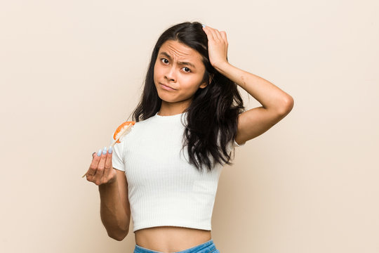 Young asian woman holding a sushi piece being shocked, she has remembered important meeting.