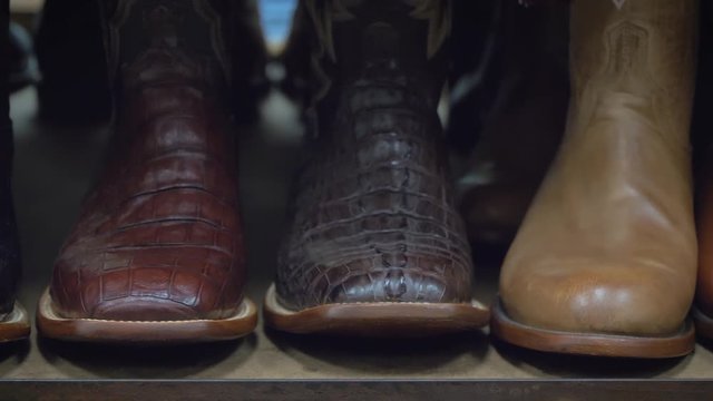 Detail shot of footwear in a row at traditional American cowboy boots. Brown cowboy boots at store display. Cowboy boots on a shelf in a store aligned, closeup. Row of cowboy boots on shelf.