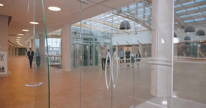 Business People Walking In Office Room Through Glass Door