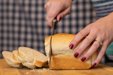 Dark brown white bread on vintage box. A white and blue background with hands cutting the bread.