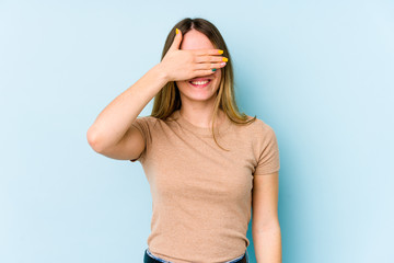 Young caucasian woman isolated on blue background covers eyes with hands, smiles broadly waiting for a surprise.