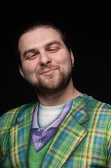 handsome stylish fooling around bearded man in green checkered blazer rolling eyes isolated on black