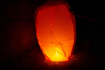 Red Sky lantern with the flames showing clearly held on the ground