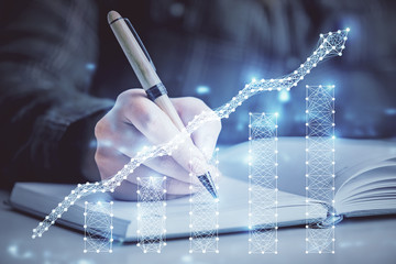 Double exposure of woman's hands making notes with forex graph hologram. Concept technical analysis.