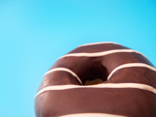 macro photo of a sweet chocolate round donut on a blue background