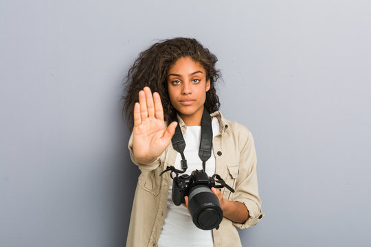 Young African American Photographer Woman Holding A Camera Standing With Outstretched Hand Showing Stop Sign, Preventing You.