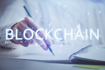 Cryptocurrency hologram, bitcoin, ico theme over hands taking notes background. Concept of...