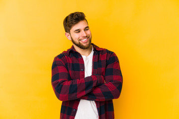 Young caucasian man isolated on yellow background smiling confident with crossed arms.