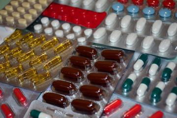 A pile of pills in blister packs. Blister packs full of multi-colored pills. Close-up on a light background. Full colored pills package. Pharmaceutical blister pack. Pack of pills with tablets.