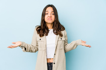 Young mixed race hispanic woman isolated doubting and shrugging shoulders in questioning gesture.