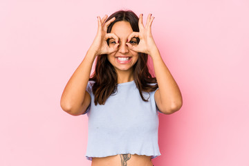 Young mixed race hispanic woman isolated showing okay sign over eyes