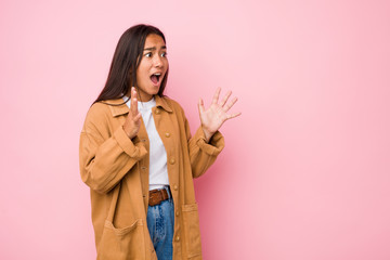 Young mixed race indian woman isolated shouts loud, keeps eyes opened and hands tense.