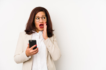 Fototapeta premium Middle age latin woman holding a mobile phone isolated is saying a secret hot braking news and looking aside