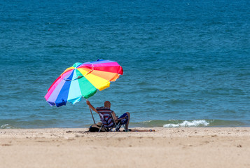 Man holds beach umbrella on a windy day at the beach
