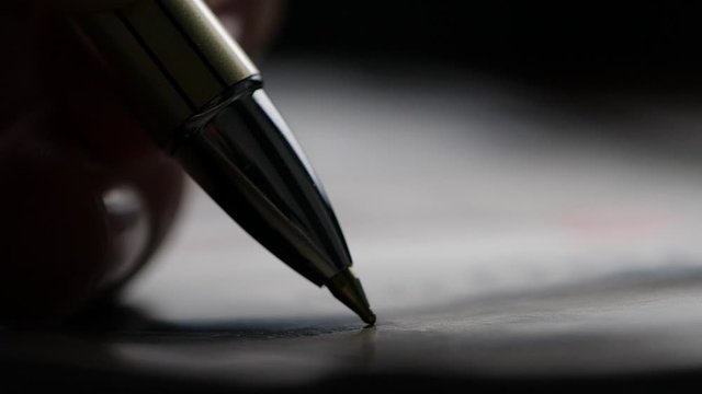 Close-up of pen writing on paper in slow motion