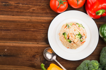 Fried rice with shrimp on the white dish on wooden table from top view
