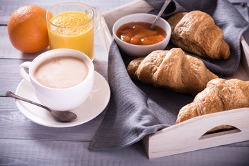 breakfast with fresh croissants and coffee on wooden table