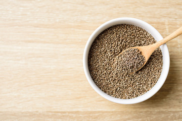 Organic perilla seeds in a bowl with spoon on wooden background, healthy herbal seed ingredient in Asian food