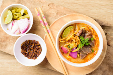 Traditional Northern Thai food (Khao Soi), spicy curry noodles soup with coconut milk and beef in a bowl, Top view