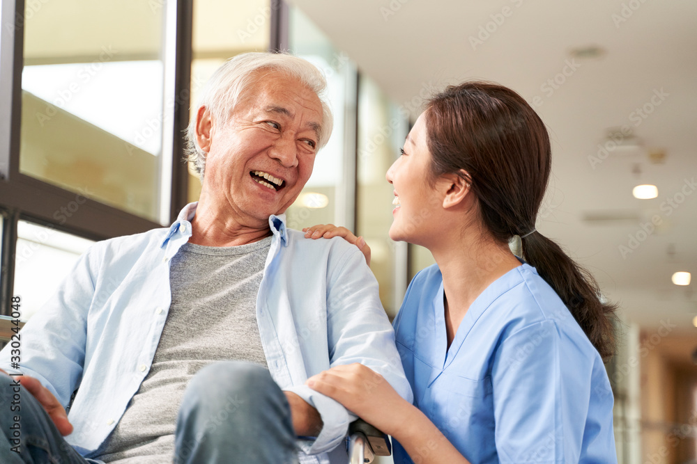 Sticker young friendly asian female caregiver talking to elderly man in nursing home