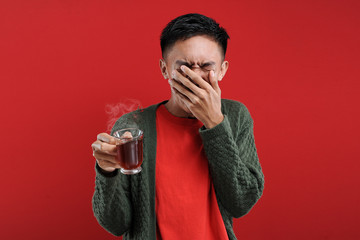 Young Asian man drinking a cup of bad tea, bitter tea,