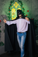 A guy in a black mask in the form of a skull and in a black cloak. Evil sorcerer with a magic wand....