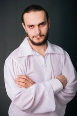 A guy with a beard in a white vintage shirt. Romantic portrait on a gray background