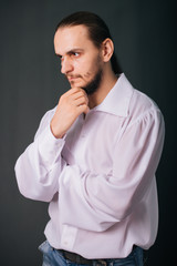 A guy with a beard in a white vintage shirt. Romantic portrait on a gray background