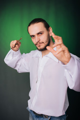 Wizard man in a white shirt conjures. A guy with long hair and a beard holds a magic wand on a...