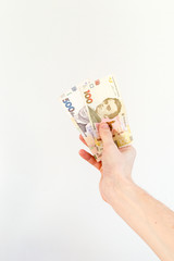 Man hand holding 100 and 500 Ukrainian hryvnia banknotes (UAH).