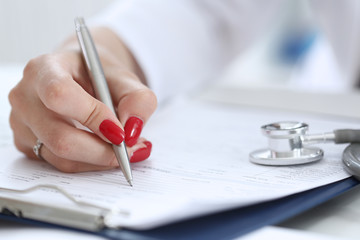 Female doctor hand hold silver pen filling patient history list at clipboard pad. Physical, exam, er, disease prevention, ward round, visit check, 911, prescribe remedy, healthy lifestyle concept