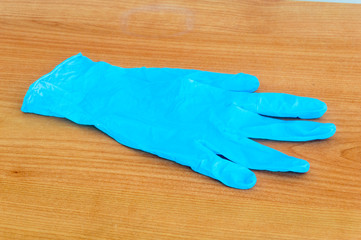 Bleu medical glove on wooden table.