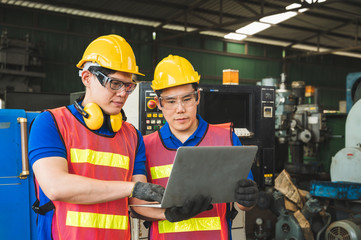 Asian industrial workers are discussing project work in large industrial plants with laptops.