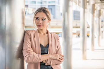 Fototapeta premium Portrait of smiling pretty young business woman with arms crossed on office background.