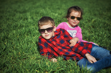 Funny children on a country walk . Brother and sister on playing on the grass .