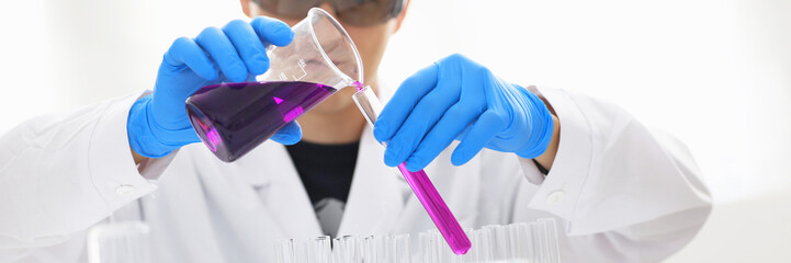A male chemist holds test tube of glass in his hand overflows a liquid solution of potassium...