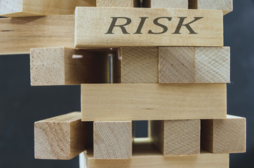 Alternative risk concept, plan and strategy in the security business by balancing a wooden stack with a form of manual control risk.