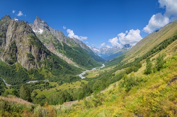 Fototapeta na wymiar Scenic mountain valley in the Caucasus Mountains, summer greens and snow-capped peaks