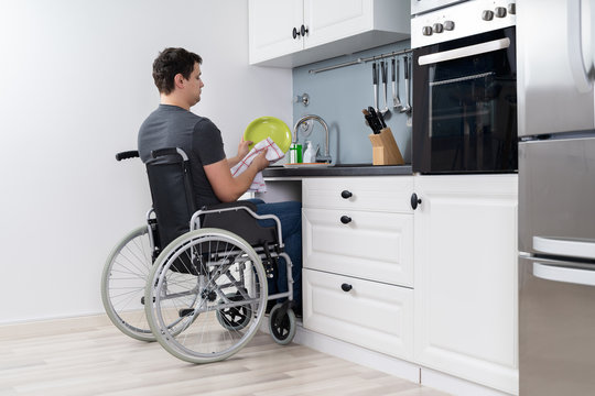 Handicapped Man Cleaning Dishes In Kitchen