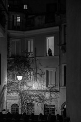 A black and white photo of a Roman alleyway and balcony