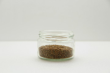 Glass jar with lentils on a white background, side view.