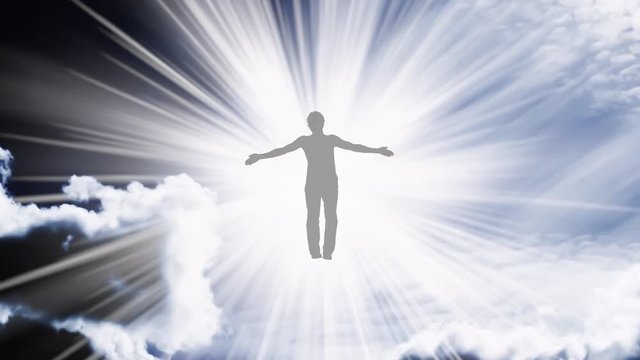 Creative 4k video with the parallax effect of the sky with moving clouds and sunlight, the silhouette of a man with spread arms, flying in bright light and dissolving in it. The concept of open mind.