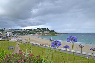 Beautiful empty beach in Brittany with traditional houses and flowers in foreground