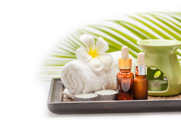 Essential oils bottle with towel and candle for aroma spa in wooden tray on white background, spa set.