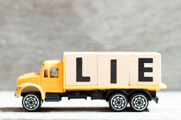 Truck hold letter block in word lie on wood background